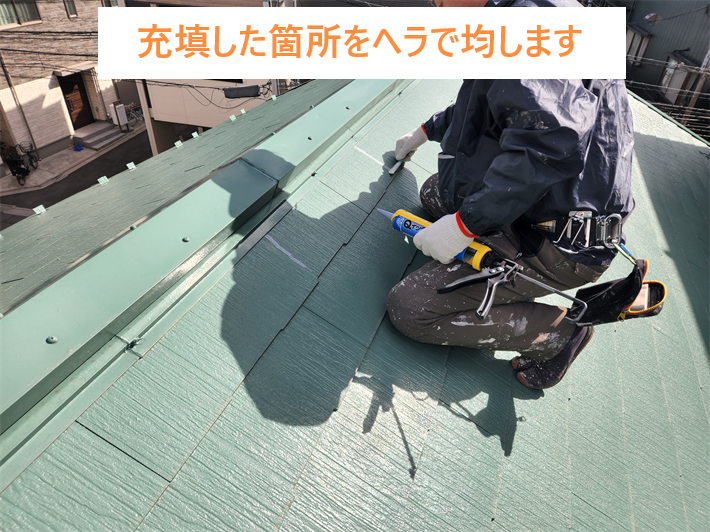 屋根補修工事にて充填したコーキング材をヘラで均します